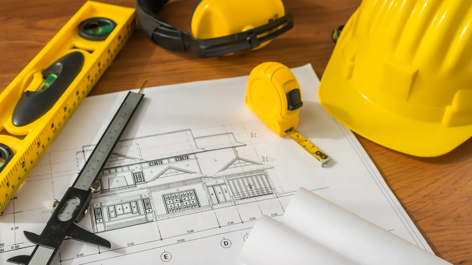 Project drawings with a spirit level, a tape measure and a hard hat